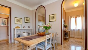 A dining area with a wooden table, chairs, and a vase of flowers. There are framed pictures on the wall and a mirror above the table. - Garden Residence Malcesine Lake View  App. G1 (Malcesine)