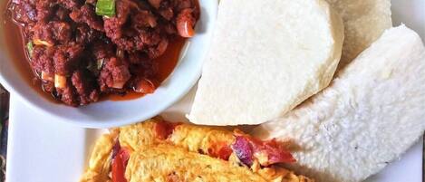 Un plato con un tazón de guiso, dos piezas de pan plano y un huevo frito.