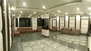 Um hall amplo com área de estar central, mesa de centro de vidro e design moderno no teto.