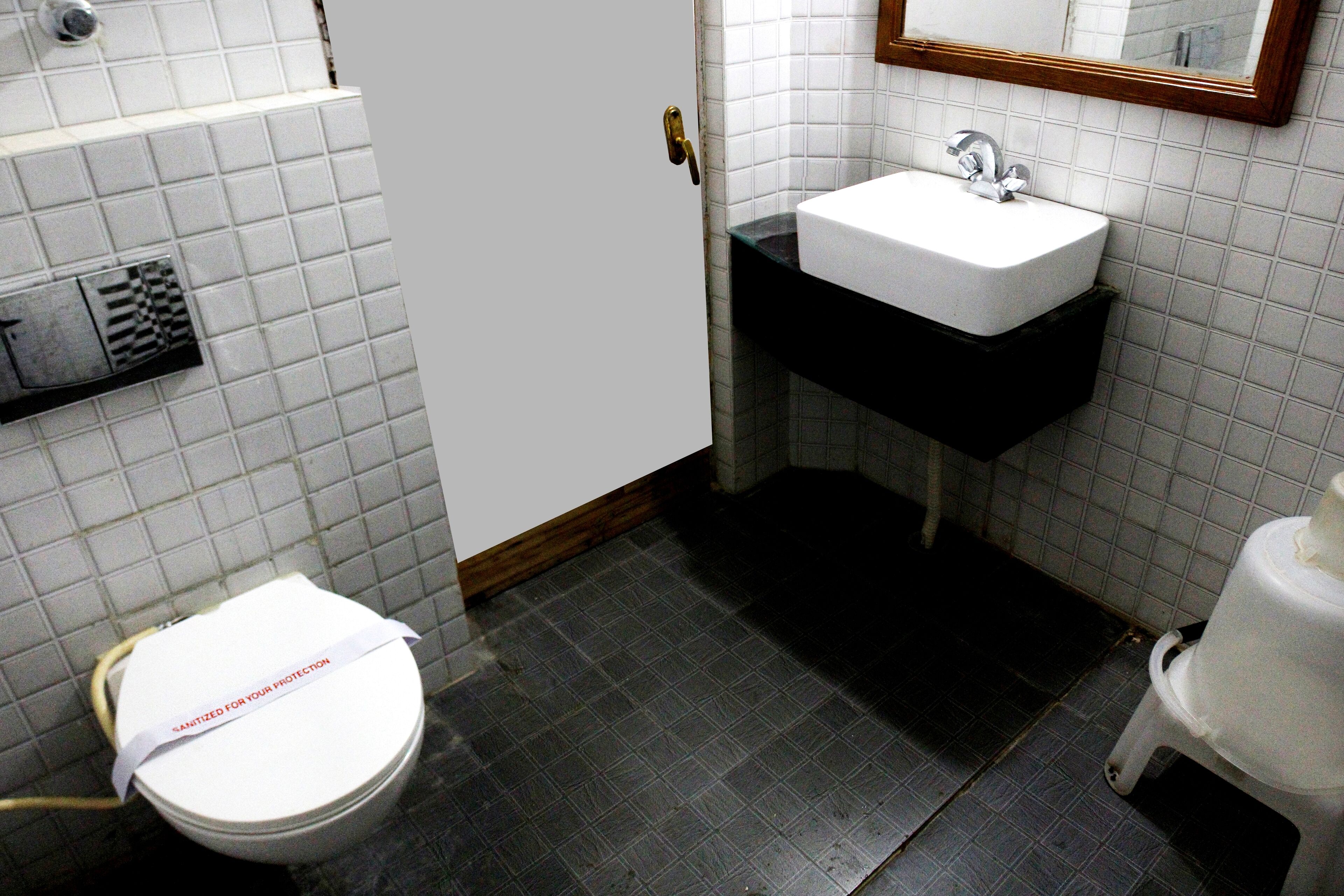 Un baño con inodoro blanco, lavabo con encimera negra y espejo sobre el lavabo.