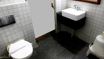 Un baño con inodoro blanco, lavabo con encimera negra y espejo sobre el lavabo.