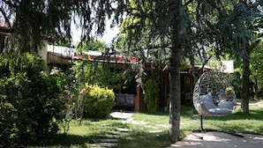 A garden with a stone pathway leading to a building with a red roof. There is a hanging chair with cushions. - Alex Village Life (Kartepe)