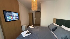 A hotel room with a bed, a TV mounted on the wall, and a wooden wardrobe. - Alex Village Life (Kartepe)