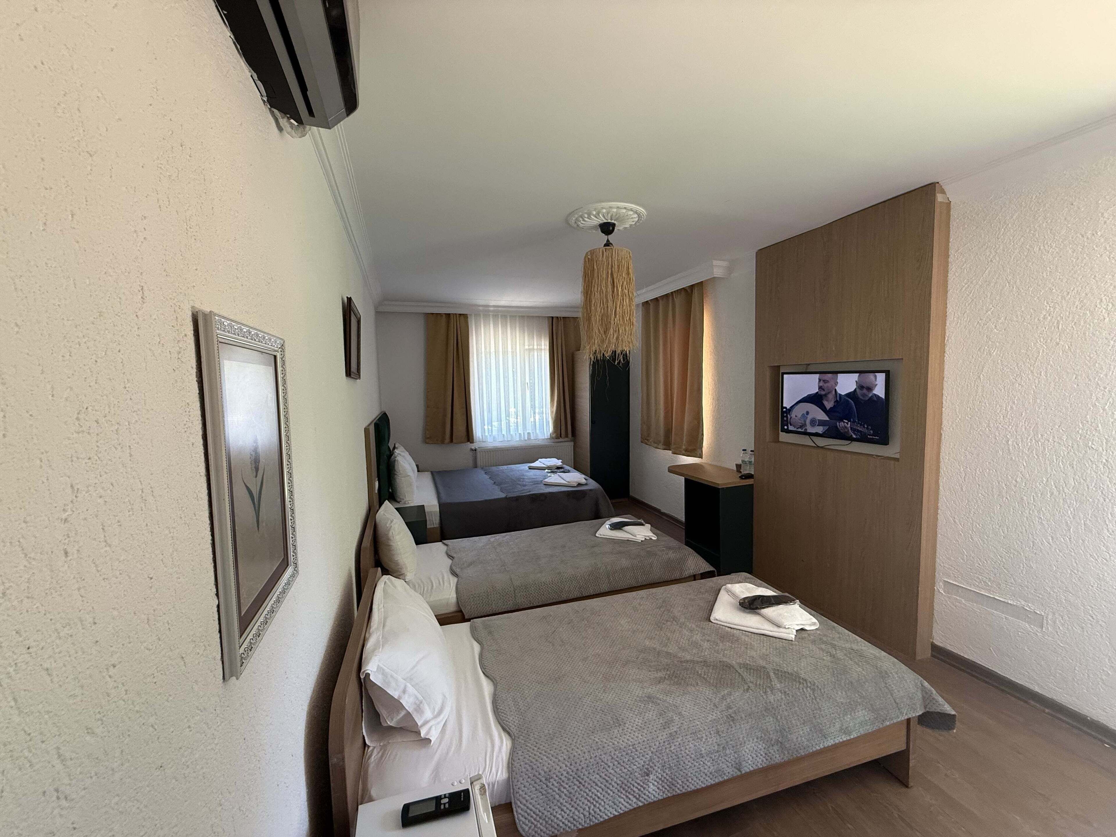 A hotel room with two beds, a TV, a ceiling fan, and a window with curtains.