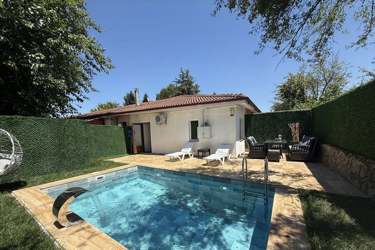 A swimming pool with lounge chairs and a small building in the background.