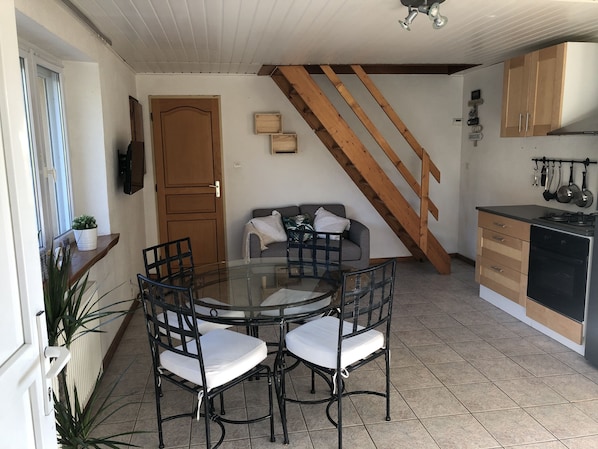 A compact kitchen with a dining area, wooden staircase, and basic amenities.