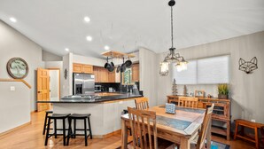 A modern kitchen with wooden cabinets, a stainless steel refrigerator, and a central island with stools. - Cutty Sark Court #1 3br 2.5ba Mountain Views 3 Bedroom Townhouse by RedAwning (Silverthorne)