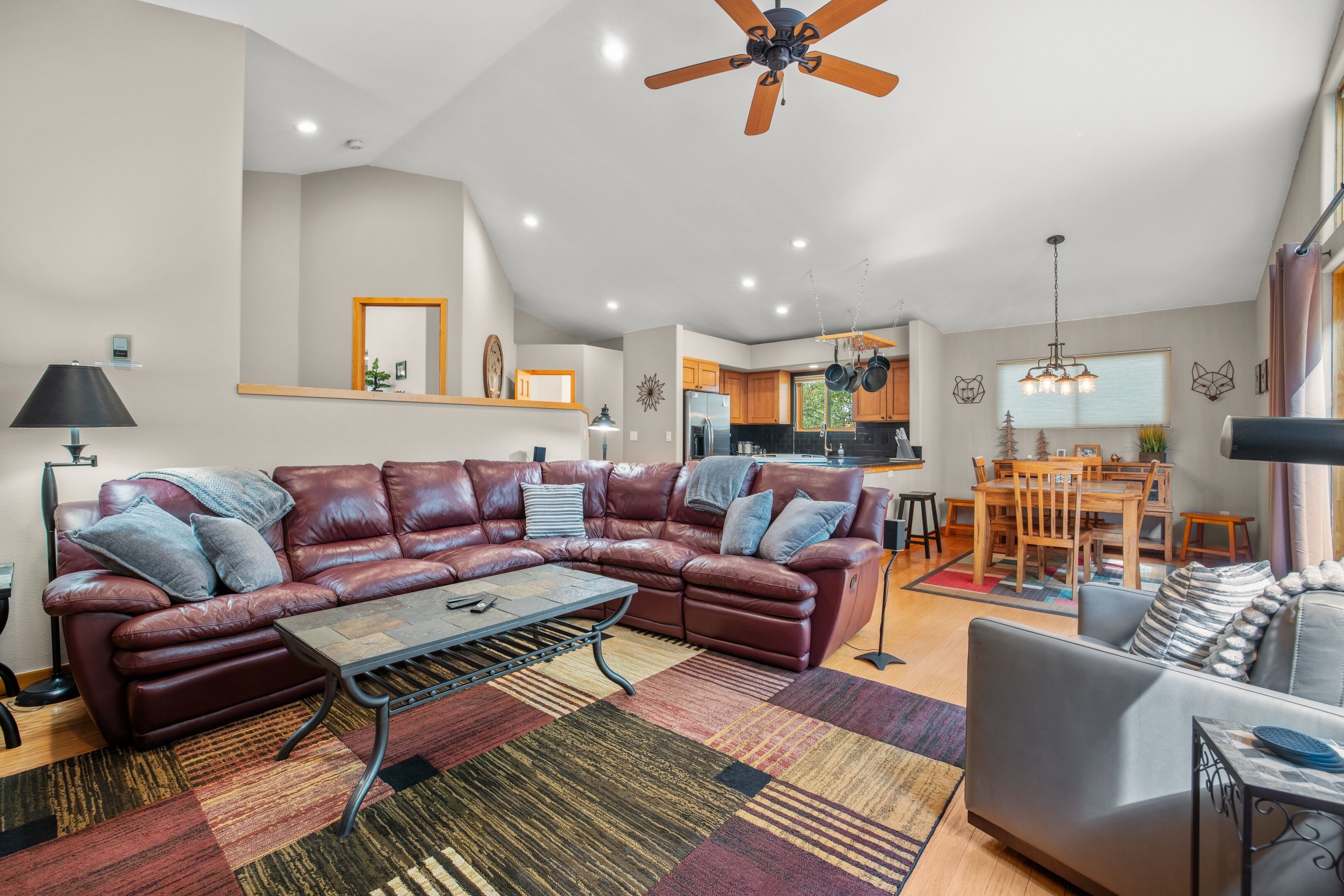 A spacious living room with a leather sofa, a coffee table, and a dining area with a wooden table and chairs.