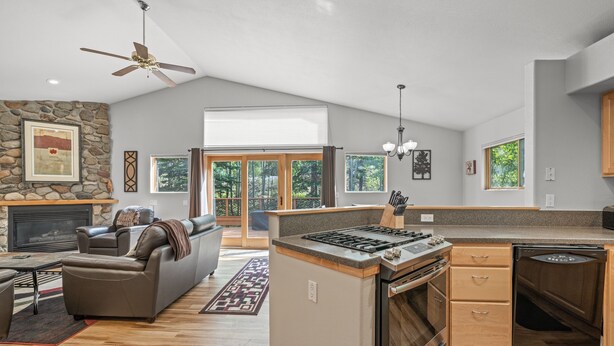 A spacious living room with a fireplace, a sofa, and a dining area with a built-in stove and dishwasher. - Cutty Sark Court #2 3br 2.5ba Mountain Views 3 Bedroom Townhouse by RedAwning (Silverthorne)