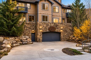 A two-story house with a stone facade, a garage, and a driveway leading to the entrance. - Settlers 2 Bedroom Condo by RedAwning (Park City)