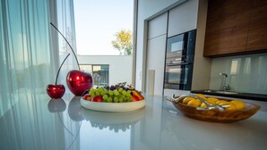 Eine moderne Küche mit einer Glasarbeitsplatte, einer Obstschale und einer roten Apfelskulptur.