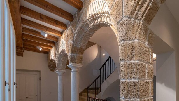 A hallway with stone arches, wooden beams, and a staircase with black railings. - Cadiz Wonderland apartment (Cádiz)