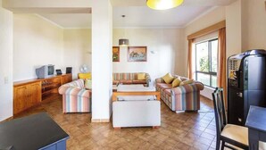 A living room with a sofa set, a coffee table, a TV, and a refrigerator.