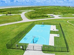 Une vue aérienne d’un terrain de basket-ball entouré de champs verdoyants et d’une route.