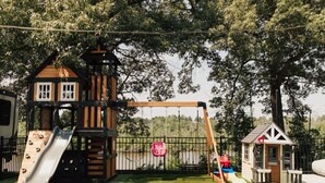 A playground with a slide, swing set, and a small building structure.