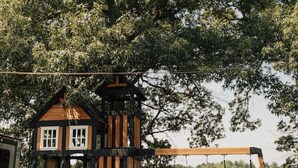 A playground with a slide, climbing wall, and swing set.