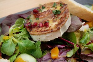 Close-up de uma salada com frango grelhado, folhas frescas e sementes de romã.