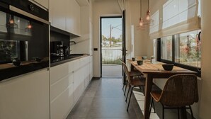 A modern kitchen with a dining area, large windows, and a view of the outdoors. - Elsa Modern Apartments. 2 Bed with Jacuzzi Apt 3 (Pogonia)