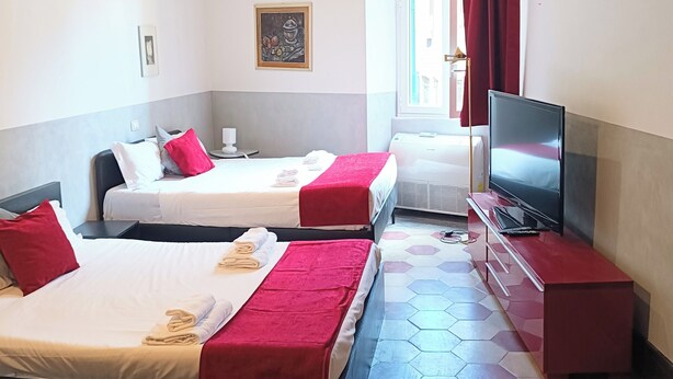 Quarto de hotel com duas camas, televisão e janela com cortinas.