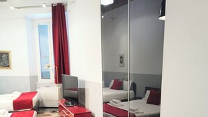 Quarto de hotel com duas camas, uma televisão e uma escrivaninha vermelha.