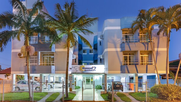 A modern hotel with a glass entrance, palm trees, and a blue and white facade. - Marazul Apart Hotel 2 (Florianópolis)