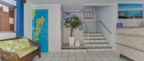 A reception area with a wicker sofa, a map on the wall, a staircase, and a plant.