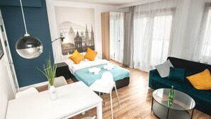 A modern hotel room with a bed, a sofa, a dining table, and a glass coffee table. - BatogoSpot Tumski (Wroclaw)