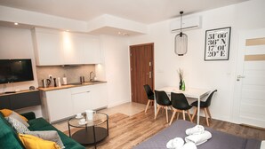 A modern hotel room with a bed, a sofa, a dining area, and a kitchen. - BatogoSpot Tumski (Wroclaw)