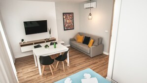 A modern living room with a flat-screen TV, a sofa with cushions, a dining area with chairs, and a yoga mat. - BatogoSpot Tumski (Wroclaw)