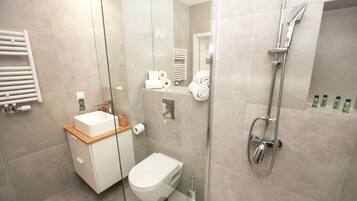 A modern bathroom with a glass-enclosed shower, a white toilet, and a sink with a wooden countertop.
