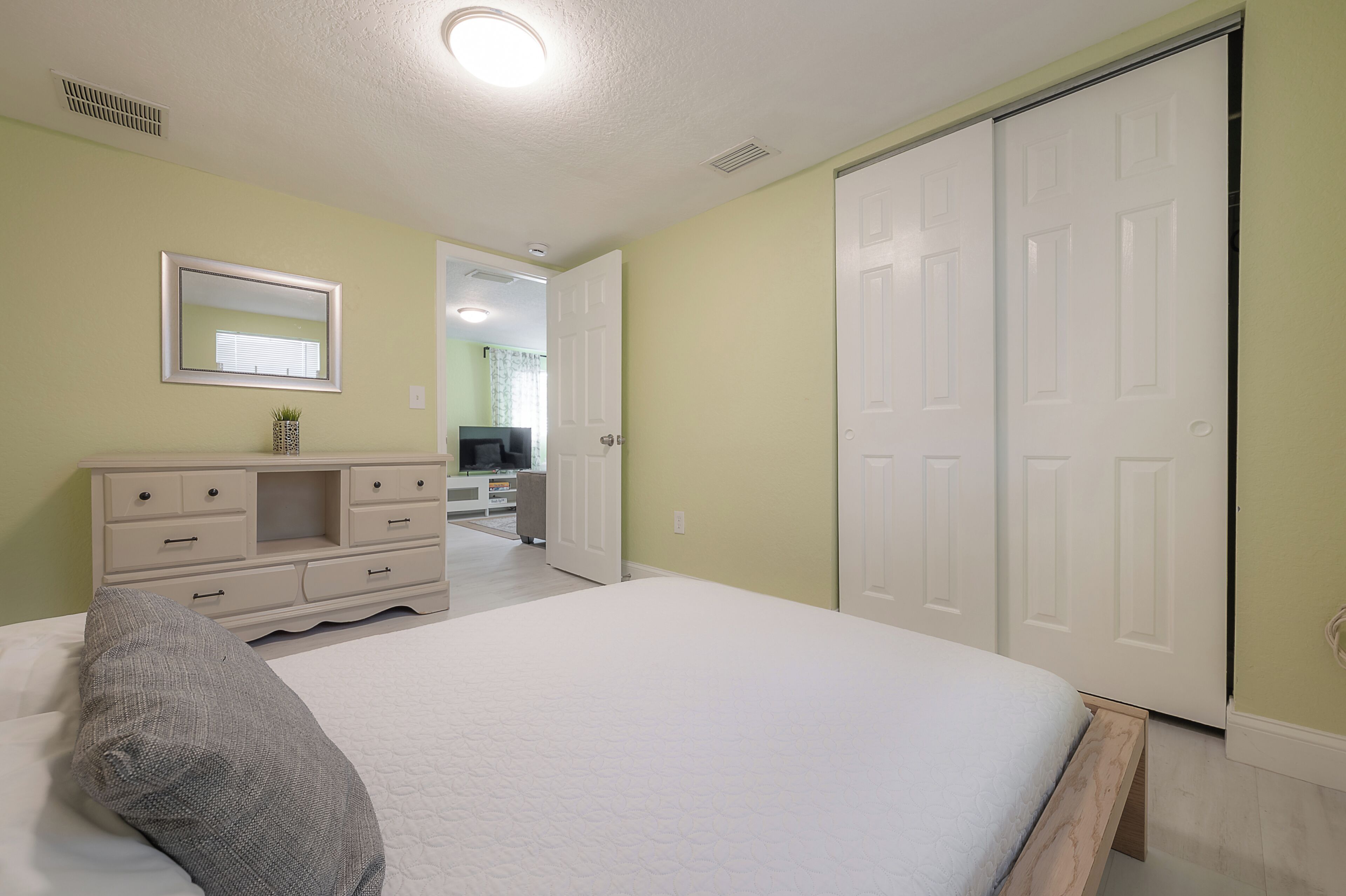 Un dormitorio con cama, cómoda, espejo y armario.