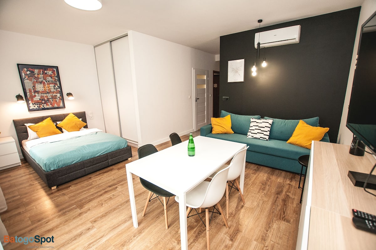 Una habitación de hotel moderna con cama, sofá, mesa de comedor y televisor.