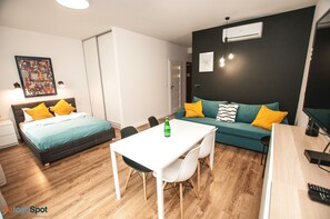 A modern hotel room with a bed, a sofa, a dining table, and a TV. - BatogoSpot Tumski 2 (Wroclaw)