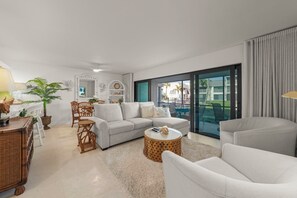 A modern living room with a sofa, armchairs, a coffee table, and a dining area with chairs and a table.