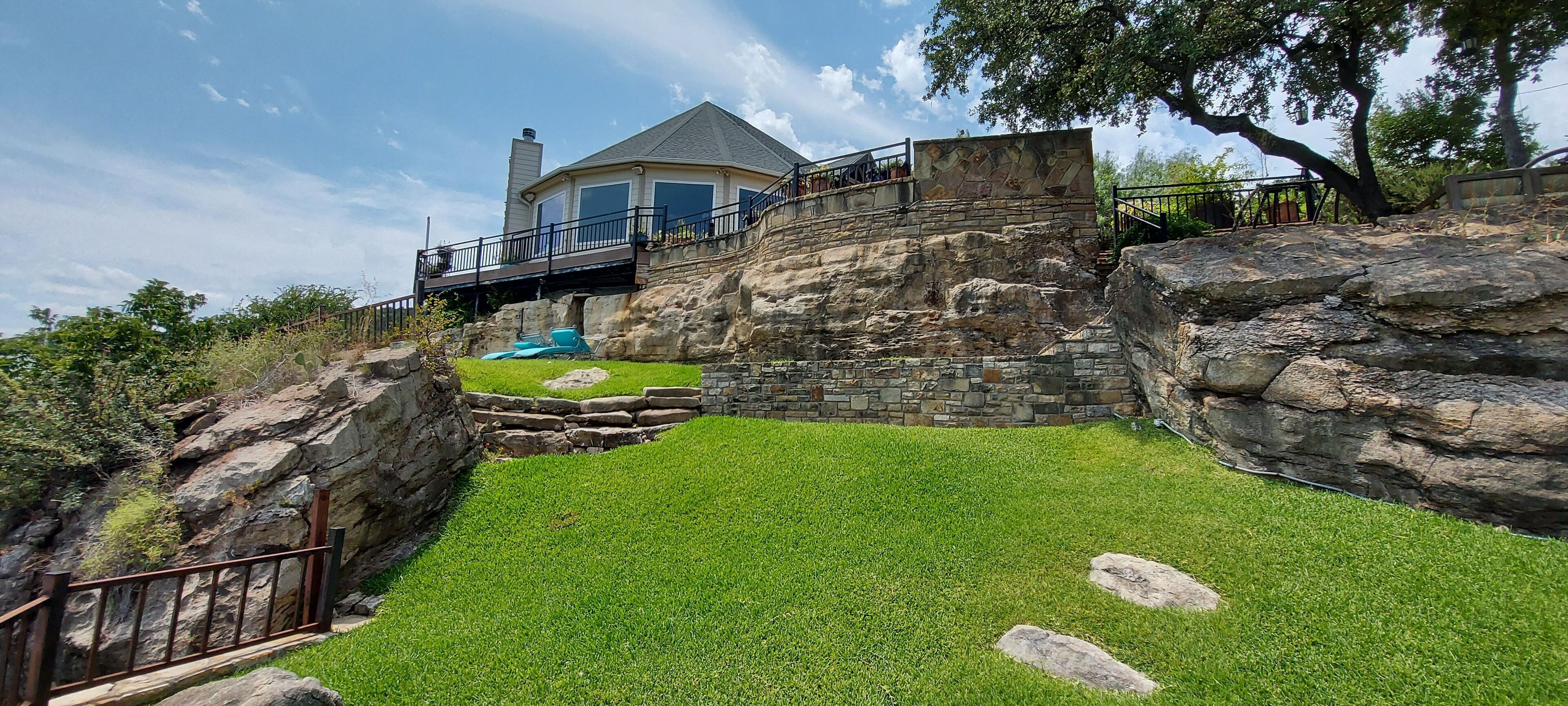 Ein Haus mit einer Steinmauer, einem Schwimmbad und einem Rasen.
