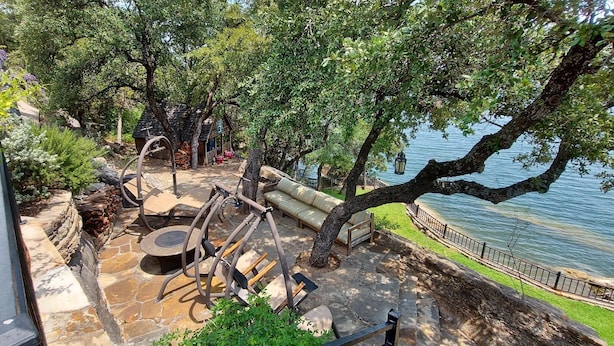 Une terrasse avec des meubles d’extérieur, un foyer et une vue sur un lac.