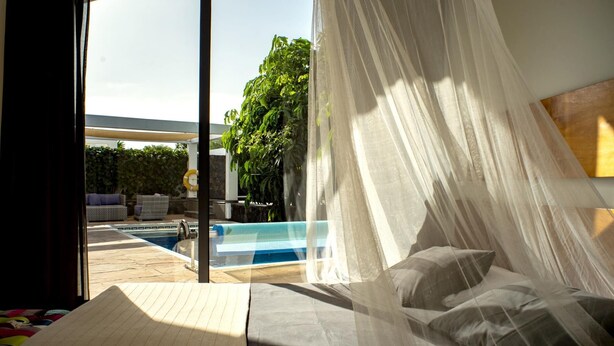 A bedroom with a large window overlooking a pool and greenery. - Casa Yuna with heated pool in El Roque (El Roque)