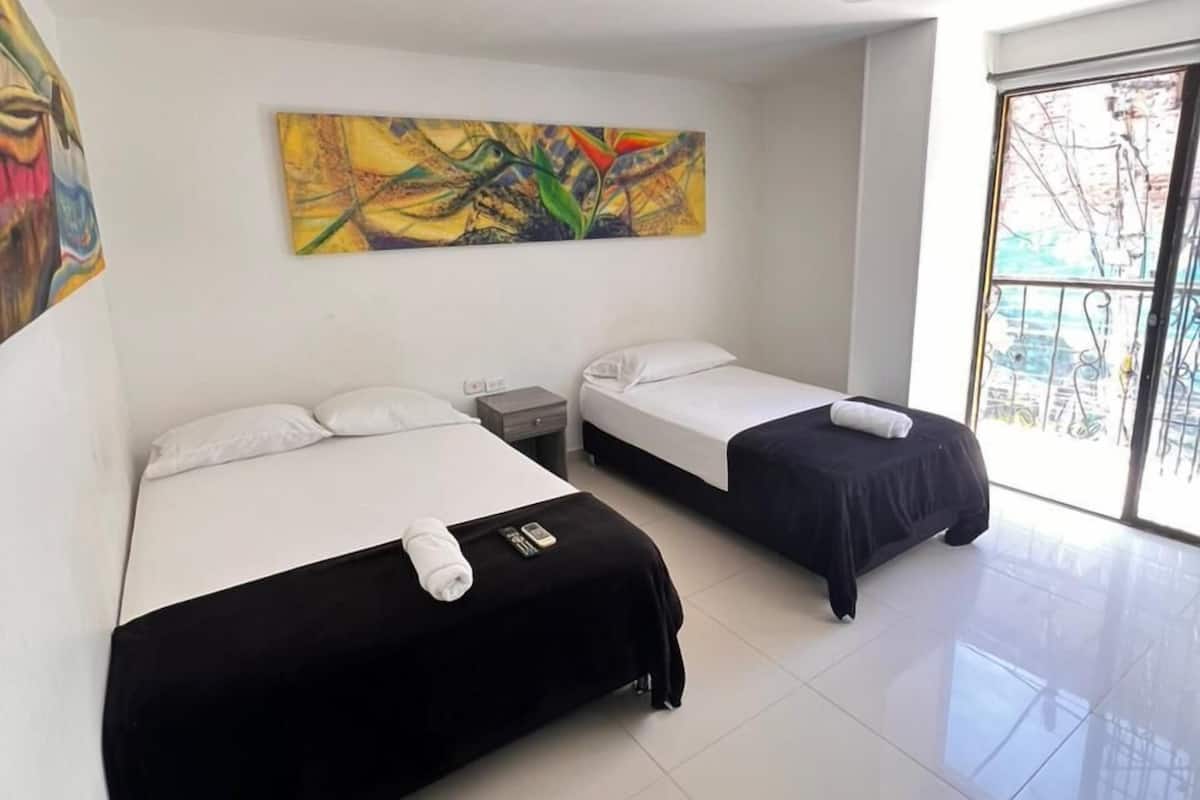 Une chambre d’hôtel avec deux lits, une grande peinture abstraite et une vue sur l’extérieur, visible à travers une porte vitrée.