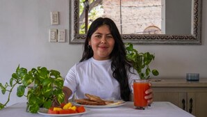 A person seated at a table with a plate of food, a glass of juice, and a potted plant. - Hotel Tayromar (Santa Marta)