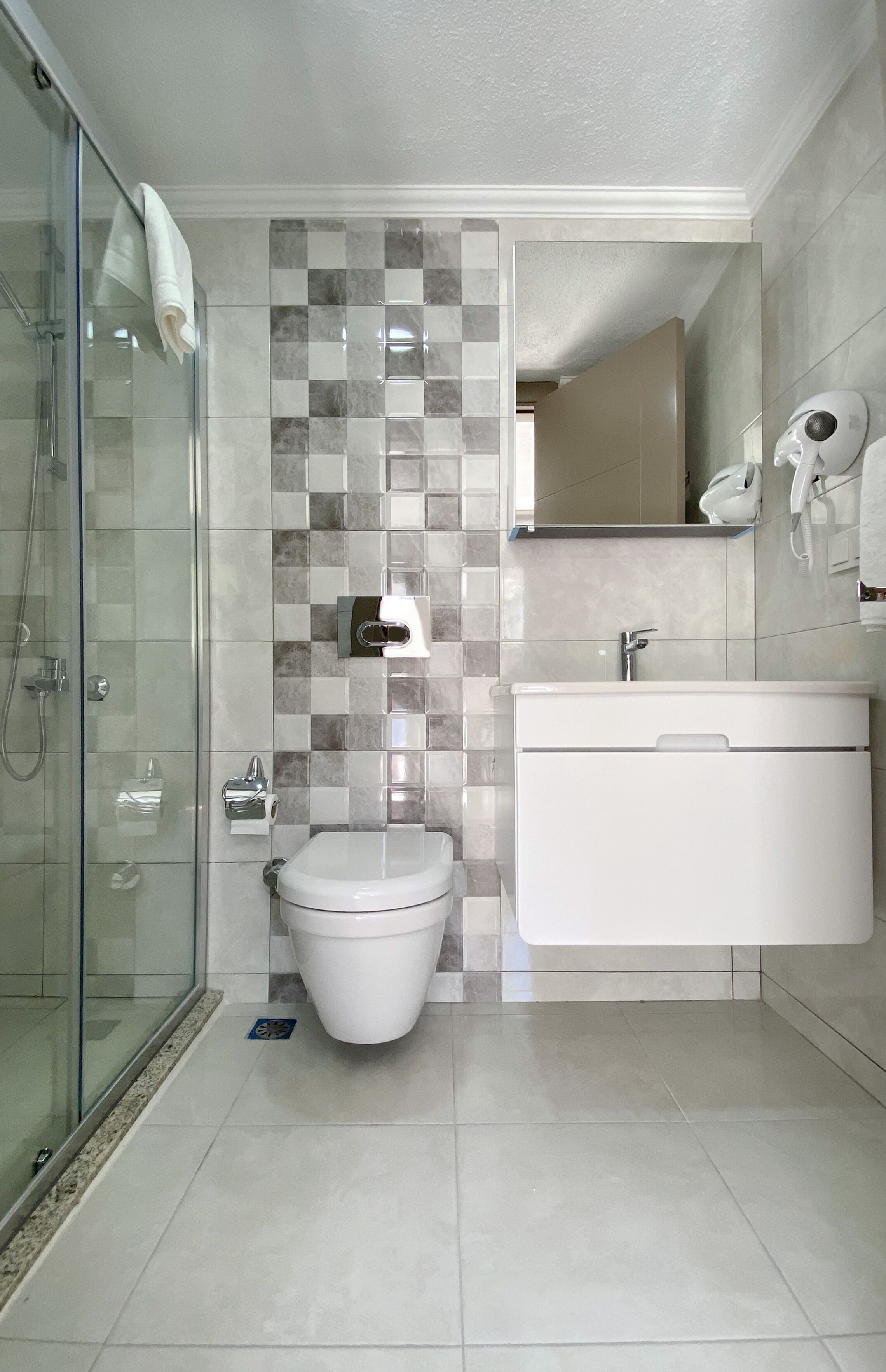 Een moderne badkamer met een douchecabine van glas, een toilet en een wastafel met spiegel.