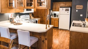 A kitchen with wooden cabinets, a white stove, and a white refrigerator. - Riverfront Mountain Cottage Retreat (Estes Park)