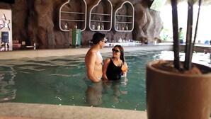 A couple in a pool with shelves of bottles in the background. - Tauá Resort & Convention Alexânia (Alexania)
