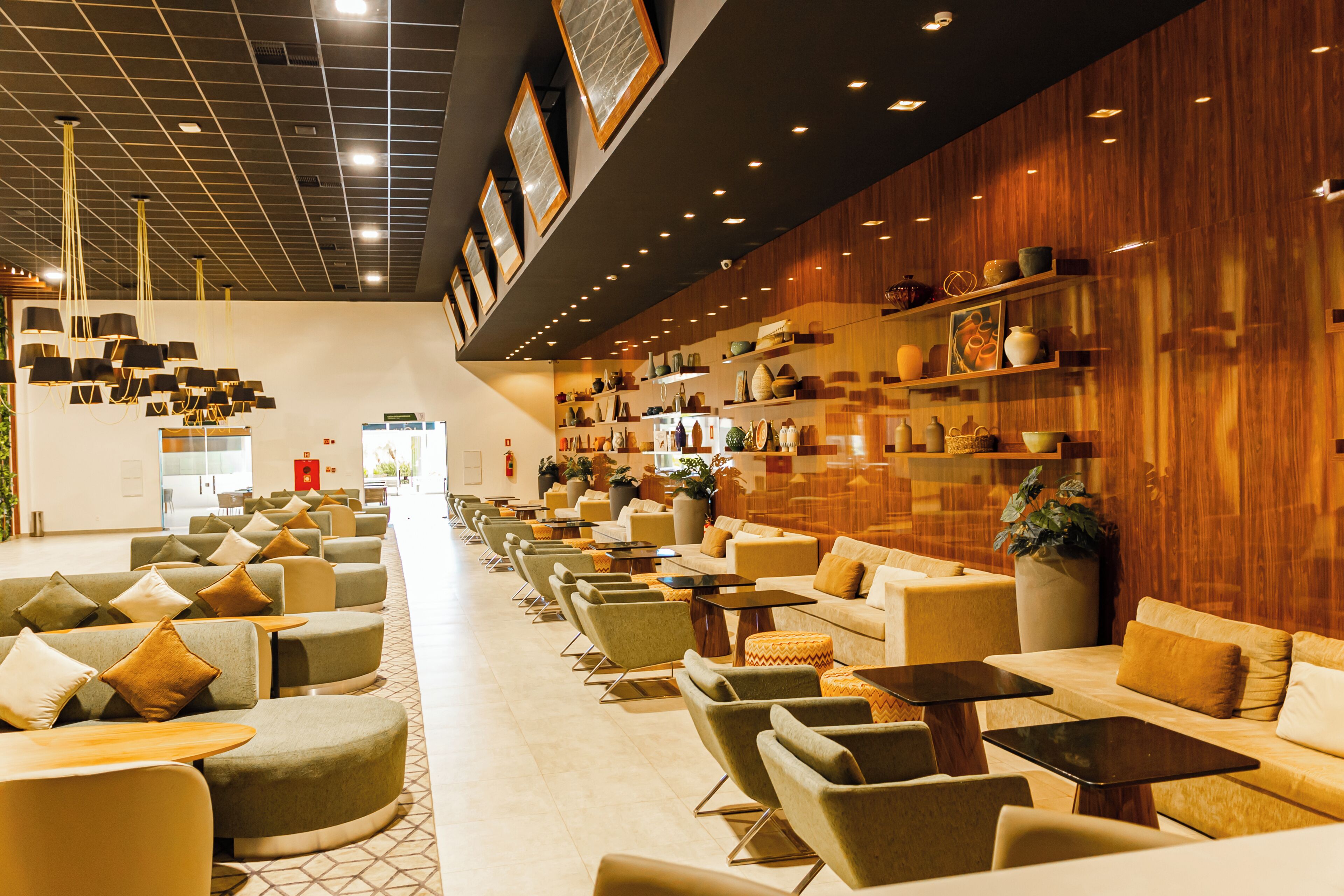 A spacious lobby with multiple seating areas, a central walkway, and a wall adorned with shelves of decorative items.