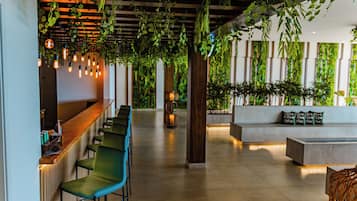A modern interior with a bar area, seating, and green plants.