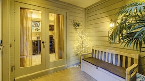 Exterior de madeira com um banco, uma porta com cortinas e um aplique de parede.