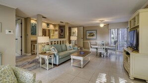 Uma sala de estar espaçosa com um sofá azul claro, uma mesa de centro e uma área de jantar com uma mesa e cadeiras brancas.