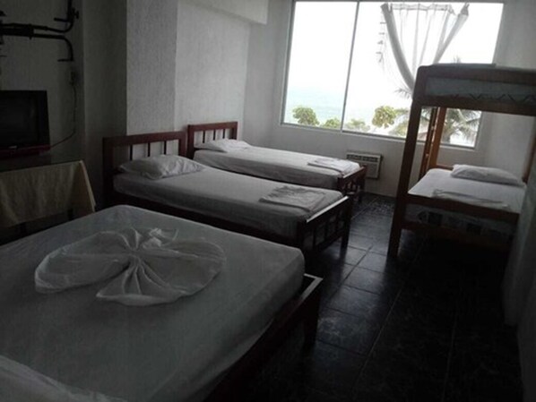 A room with two single beds, a bunk bed, a window with a view, and a TV. - Grand Hotel Paraiso Atacames (Atacames)