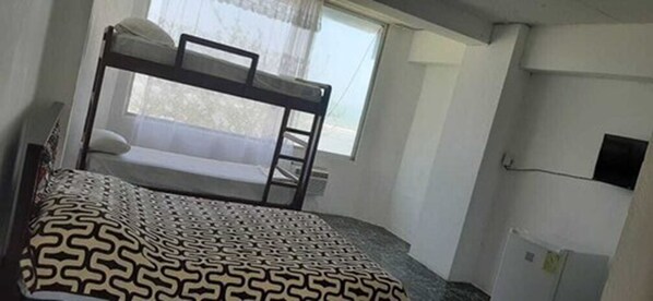 A bunk bed room with a patterned bedspread, a window with curtains, and a wall-mounted TV. - Grand Hotel Paraiso Atacames (Atacames)