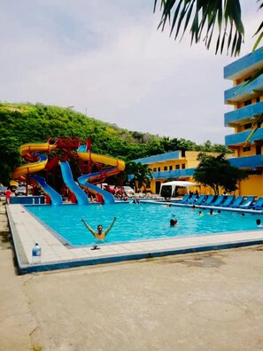 A swimming pool with a water slide, surrounded by a building with multiple balconies. - Grand Hotel Paraiso Atacames (Atacames)