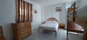 A bedroom with a wooden bed, a dresser, a nightstand, and a chair. - Grand Hotel Paraiso Salinas (Salinas)
